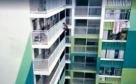 ■关永泰拉住栏杆逐层往下爬，双手多次悬空。