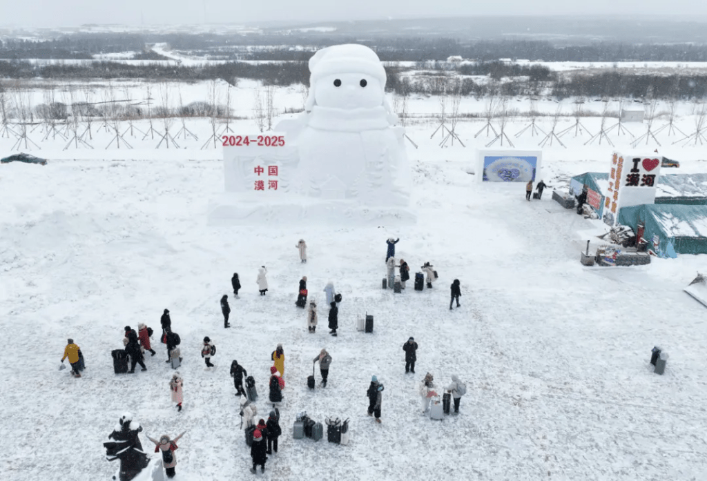 11月26日，遊客在漠河站站前廣場與大雪人合影（無人機照片）。新華社