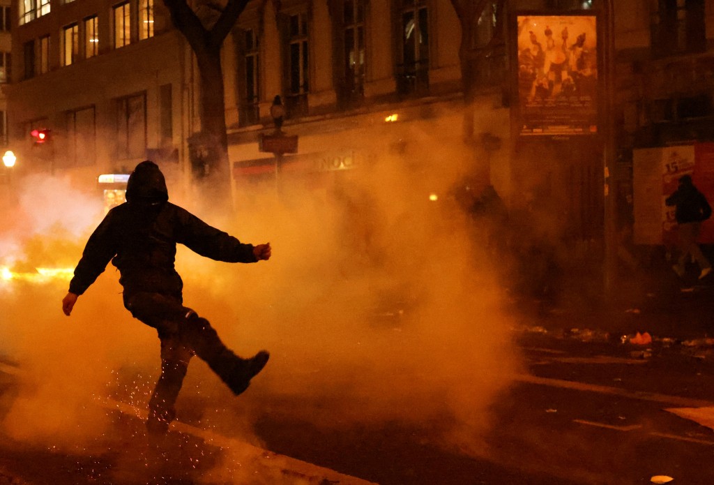 法国退休改革引发的全国示威进入第9天，巴黎一名戴口罩的示威者在催泪烟中踢走异物。  路透社