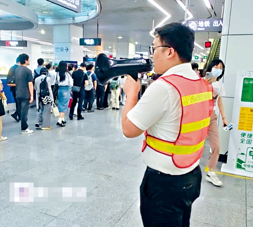 深圳地鐵福田站工作人員用擴音器疏導人潮。