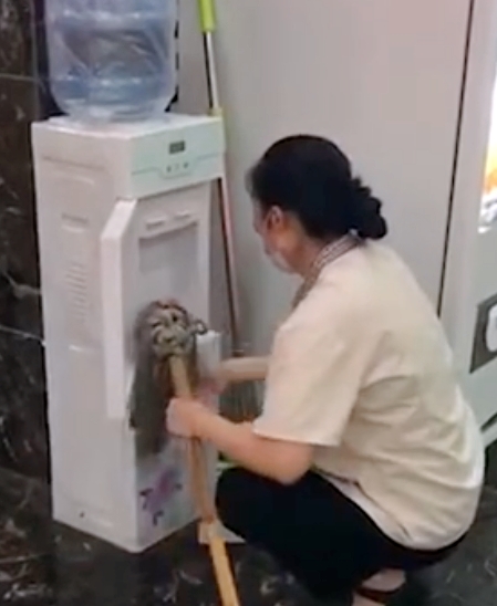 清潔女工用地拖擦拭飲水機。網圖