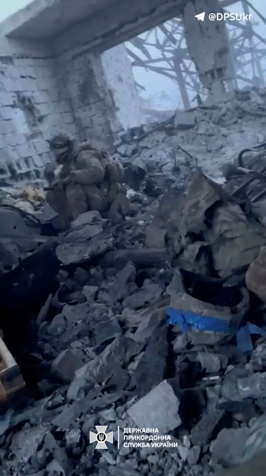 烏克蘭士兵坐在幾乎全毀的建築物瓦礫中。 路透社