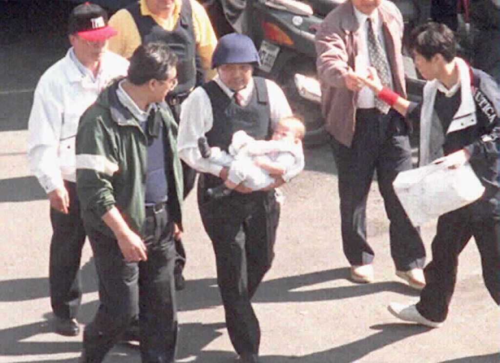 1997年南非武官挾持案，侯友宜（中間白衣者）抱著南非武官幼子離開官邸的照片。 中時
