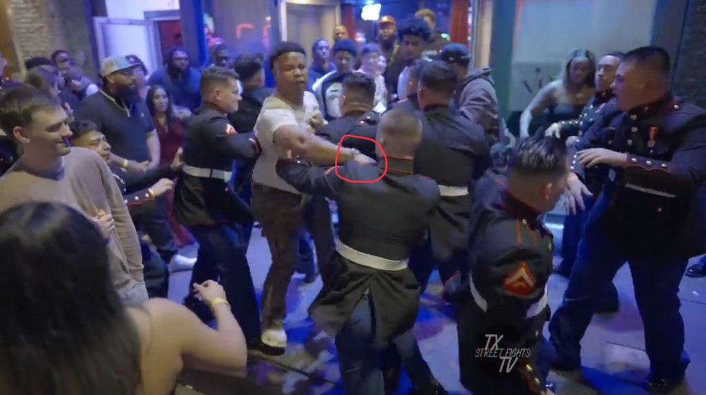 穿淺色短袖T恤、白波鞋的男子向陸戰隊員臉部揮拳。 Youtube