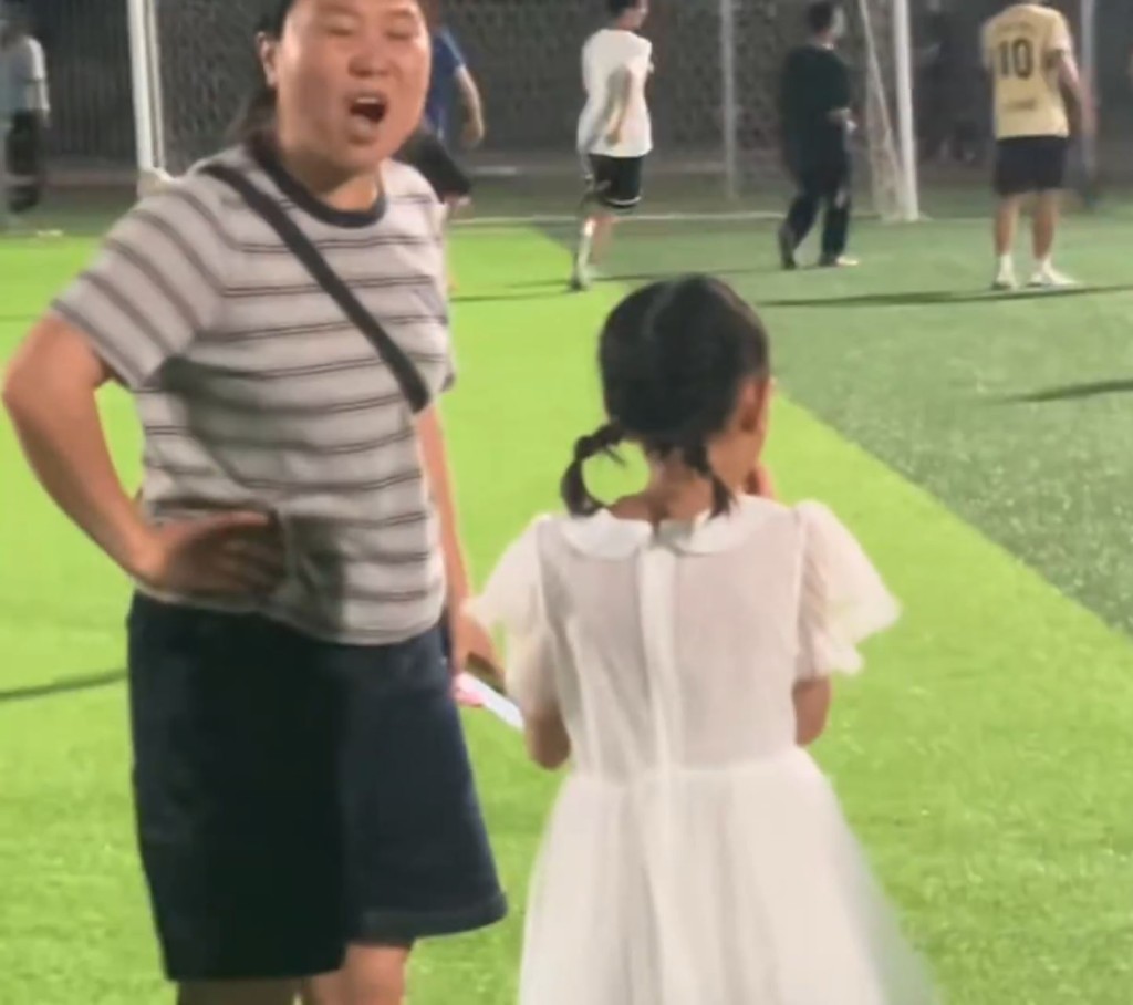 宝妈不顾危险带孩子穿越足球场，女儿被球踢中即情绪失控拒绝离开。