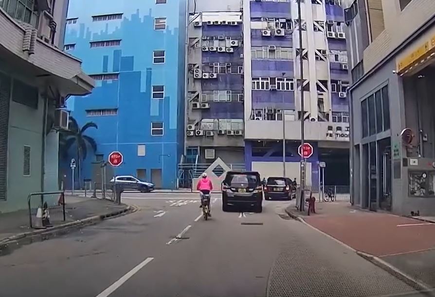 一名約50歲身穿粉色風褸的單車女子於馬路行駛。（圖片來源fb 馬路的事討論區）