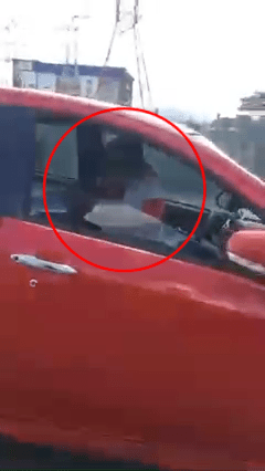 红色私家车的车窗半开，车内一对男女「女上男下」，坐在前排乘客座椅。