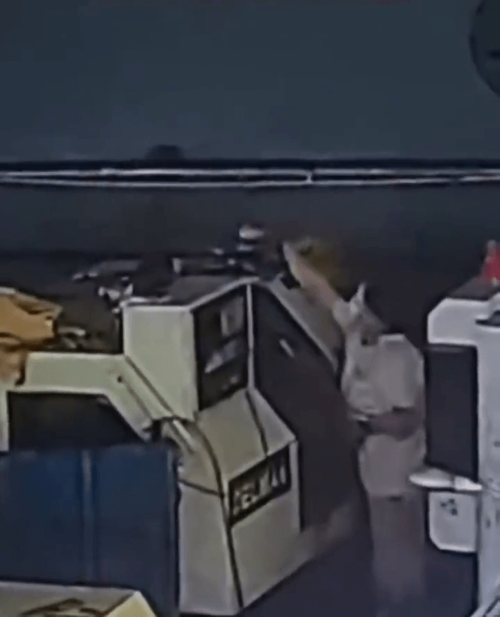 闭路电视画面显示，女员工在一机器旁将同事的水杯拿下。