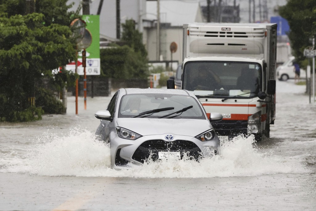 日本南部福岡縣久留米市，車輛在被洪水淹沒的街道上行駛。AP