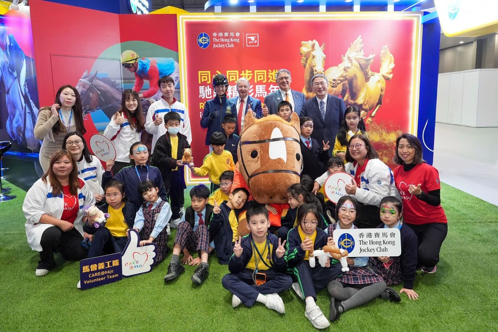 香港特別行政區政府政務司副司長卓永興 (後排右一)、香港賽馬會副主席兼浪琴香港國際馬術盛典主席及中國香港馬術總會會長黃嘉純 (後排右二)、香港賽馬會行政總裁應家柏 (後排右三)及馬會青少年馬術隊成員王嘉莉 (後排右四)，與馬會義工隊及進場觀賽的青年及基層團體，於馬會互動攤位合照。