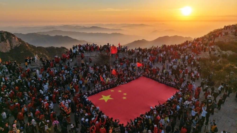 劳动节泰山之巅旗海飘扬，两万游客齐声祝愿「国泰民安」。 泰山日报