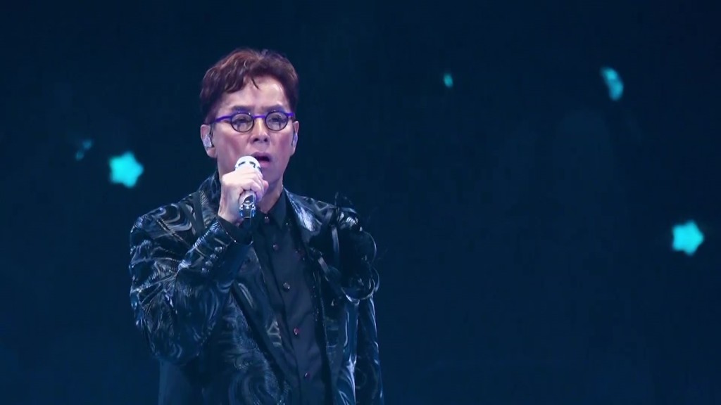 譚詠麟換上深色暗紋西裝深情演繹經典名曲，唱功依然震撼人心。