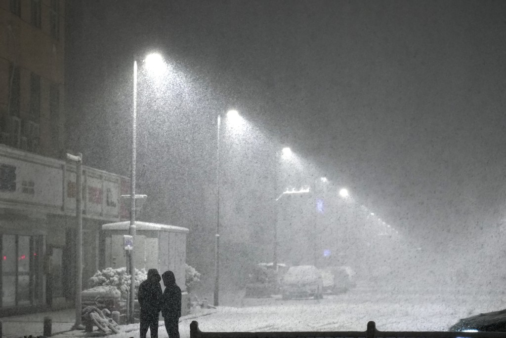 12月11日凌晨，两名市民冒雪前行。 新华社