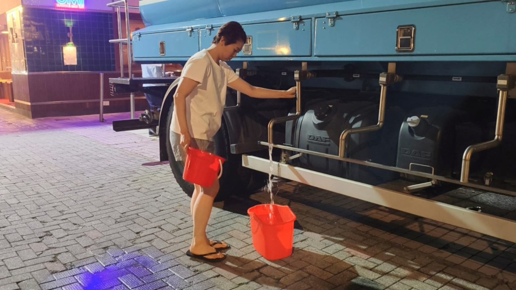 有女住戶到水車取水。 有女住戶到水車取水。