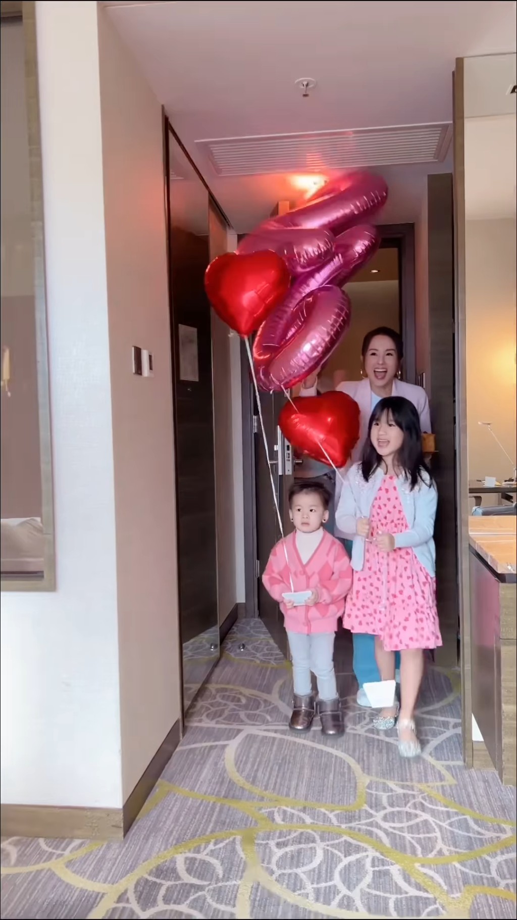 杨洛婷捧著蛋糕、老公Tim手持鲜花，而一对子女就拿著心心及26数字的气球冲入酒店房，向杨母大叫「Happy birthday」。