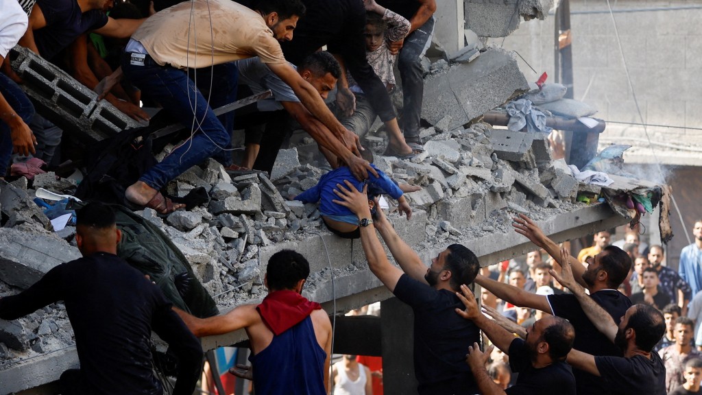 汗尤尼斯住宅建築被炸出大洞，民眾在瓦礫中抱出一個孩子。 路透社