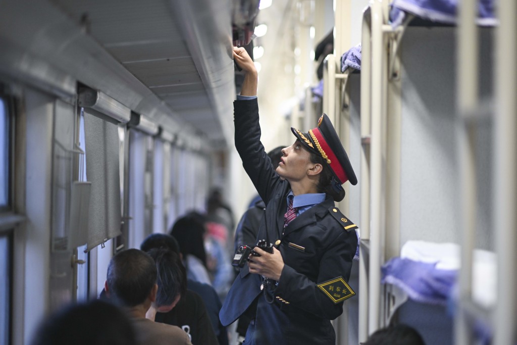 艾尔开牙·多力开在由喀什开往成都西的列车上检查旅客行李摆放。 新华社
