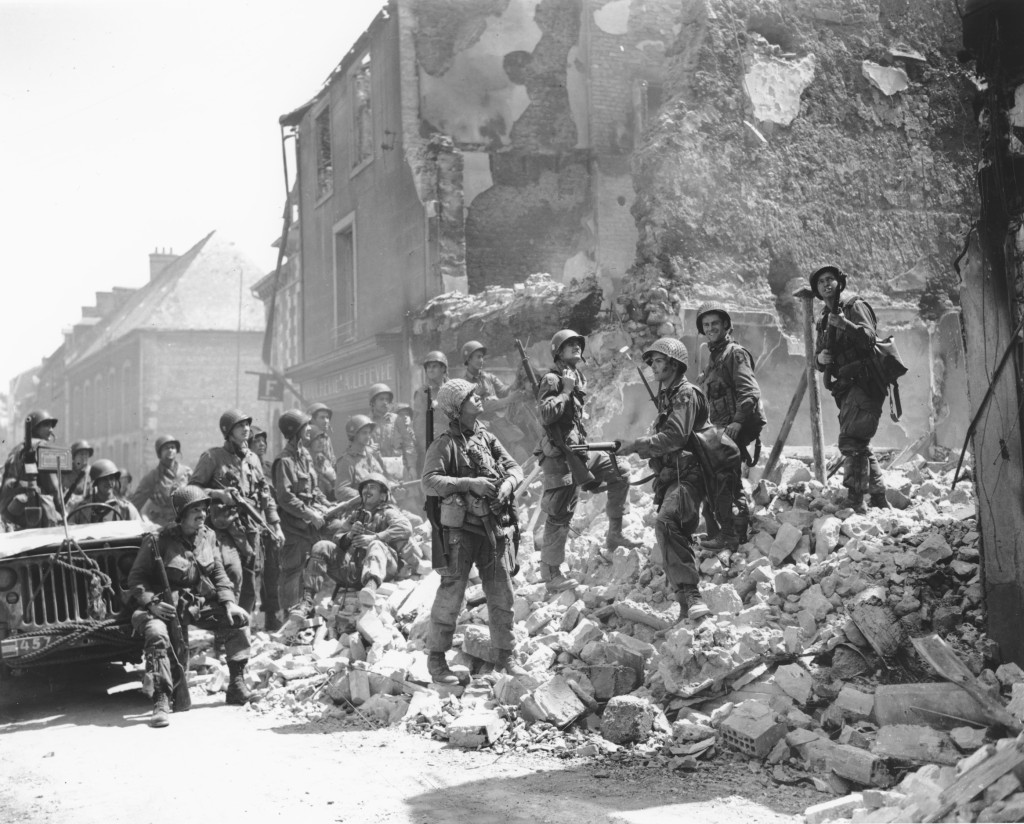 1944年6月15日，美国士兵站在法国诺曼第地区卡朗坦的一座房屋废墟上检查受损情况。美联社