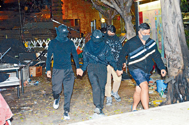 兩名城大男生在義務急救員陪同下離開理大。