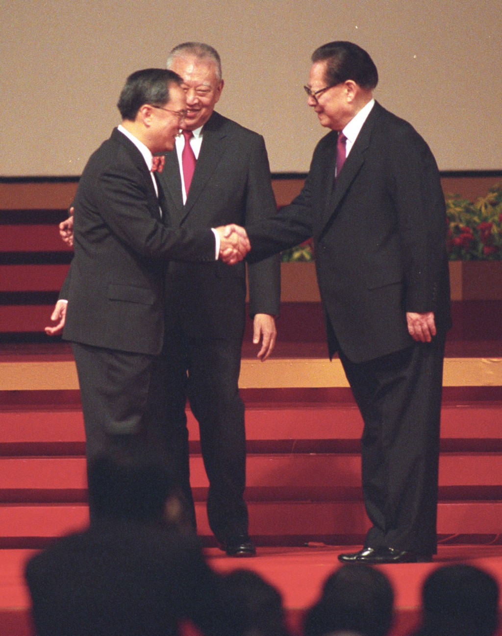 江澤民（右）與獲委任為政務司司長曾蔭權（左）握手。資料圖片