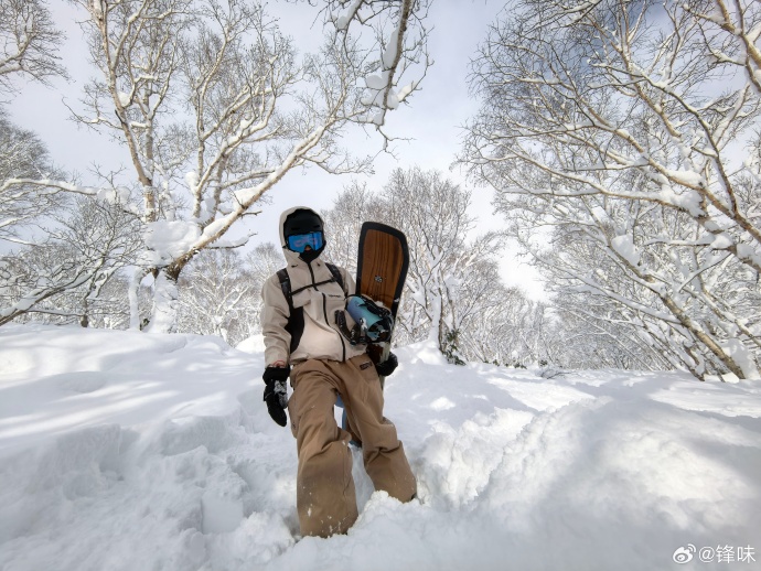 Lucas身穿燕麥色滑雪服及淺啡色長褲，同樣單手拎住滑雪板站在雪地中央留影。