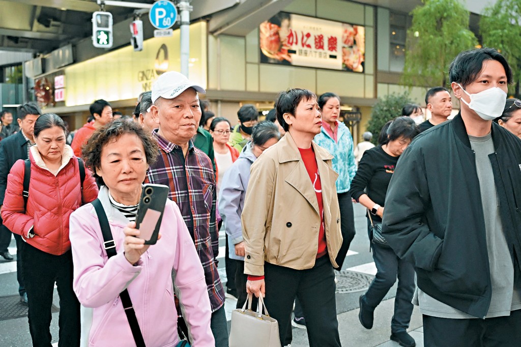一群中國旅行團成員在昨日東京銀座購物區過馬路。