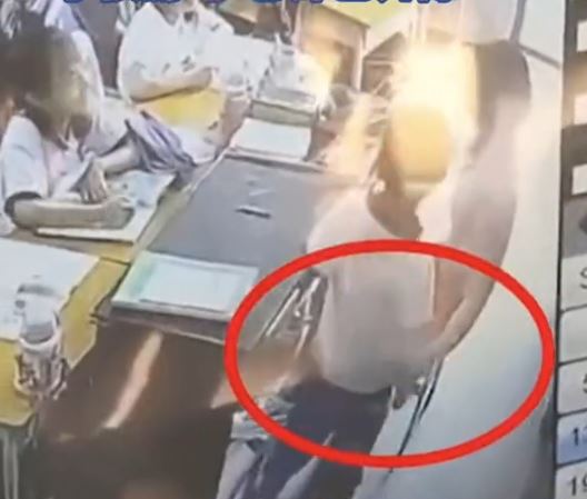 监控片段显示，坐著的女教师捉著男生，要全班26人轮流拍打该男生。