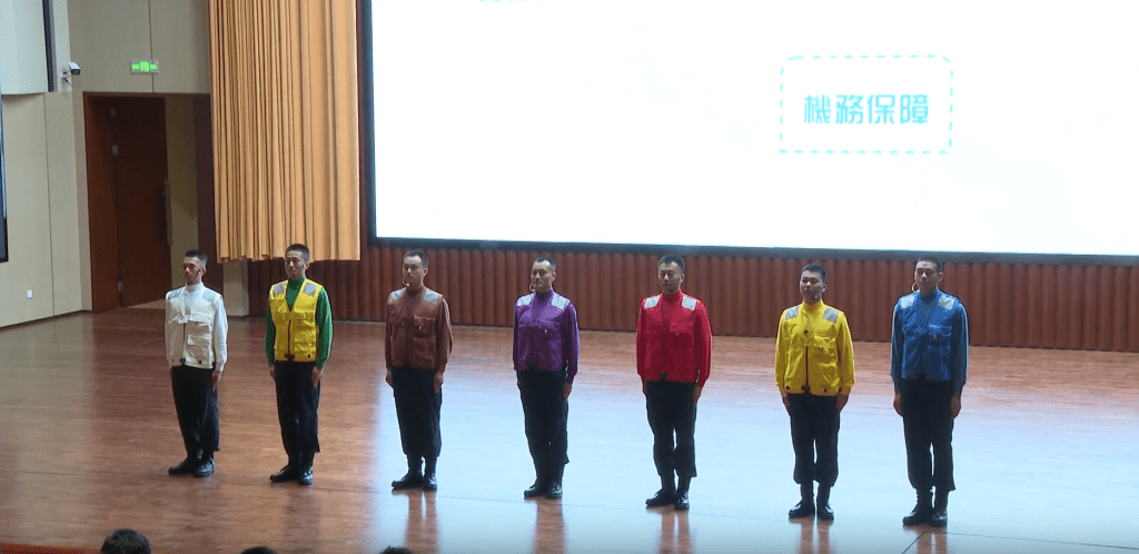 7名分別穿上白色、綠色、棕色、紫色、紅色、黃色及藍色識別服的「甲板彩虹人」艦員。