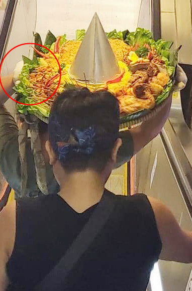 两人搭扶手电梯时，更用头顶起整盆食物。