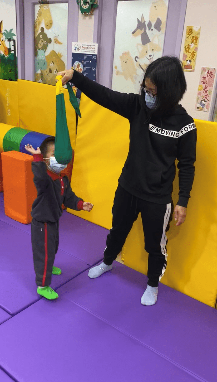 想訓練上肢肌力，家長可以在家將球拿在較高位置，讓孩子提手拍打。