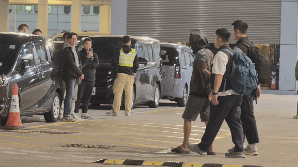 疑犯被黑布蒙頭，雙手扣上金銬被帶離警署。黃文威攝