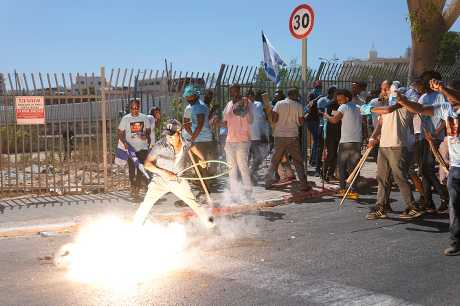 以色列警察投掷的一枚眩晕手榴弹在厄立特里亚示威者旁边爆炸。美联社