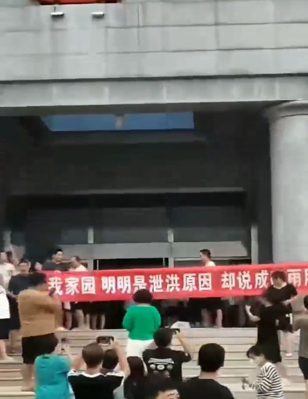 一批村民到政府大楼抗议在现场高举红色横幅布条。网图