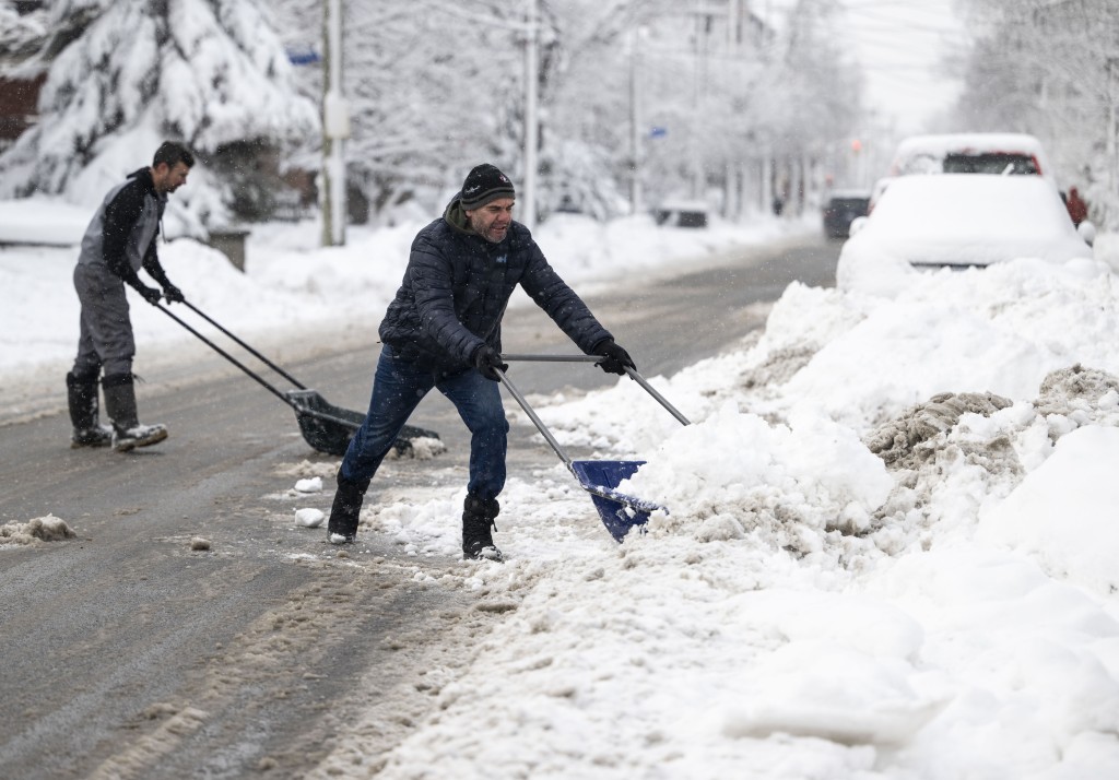 暴风雪过后，居民使用雪橇铲清理路面。AP