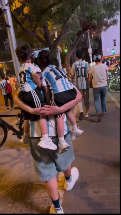一男子背兩小童觀看阿根廷的比賽。