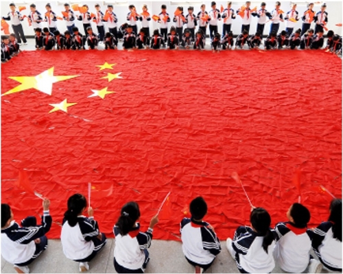 学生们专心地在地面并出巨型国旗。网图