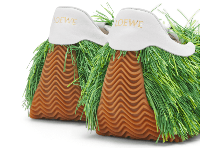 鞋款出自 LOEWE 2023 春夏男装系列，以柔软的帆布为基底并采全手工嵌入质地光滑且韧性十足的拉菲草（Raffia）诠释绿意盎然的茂密草丛。官网图