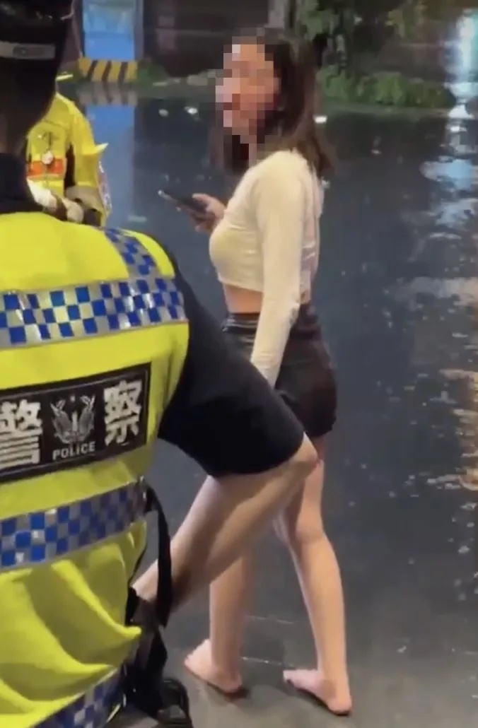 白衣女赤脚向警员讲述被殴经过。