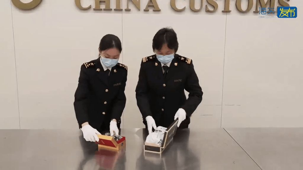 關員進一步查驗,購物車中查獲兩個煙盒。 海關發布 關員進一步查驗,購物車中查獲兩個煙盒。 海關發布