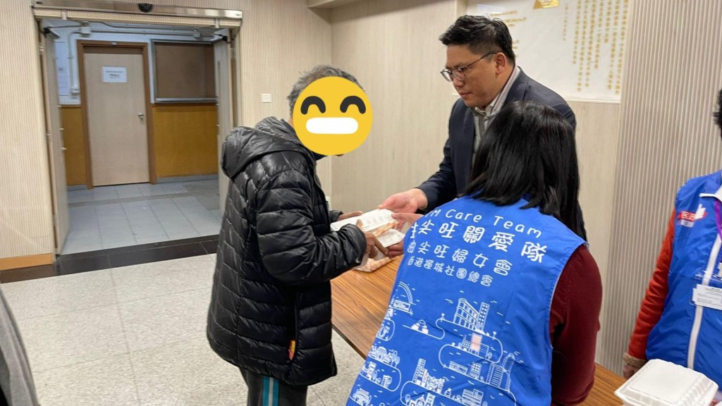 梁宏正向入住的市民派發熱飯。