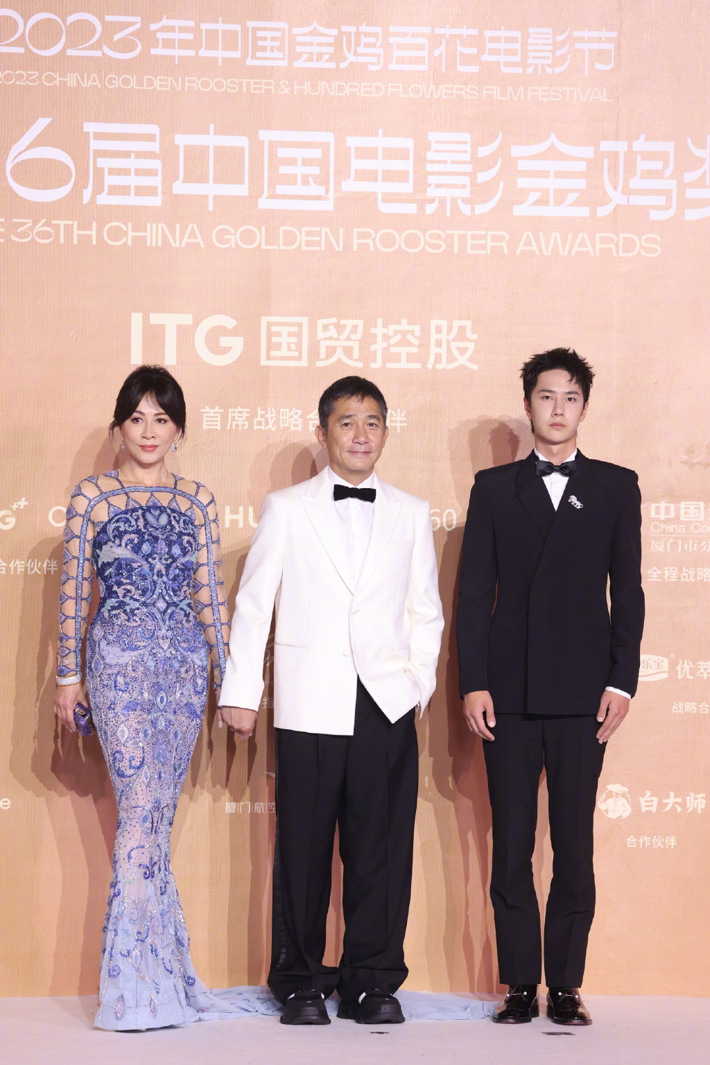 凭《无名》角逐金鸡奖「最佳男主角」的梁朝伟（中），再次穿上白西装加黑煲呔亮相红地毡。
