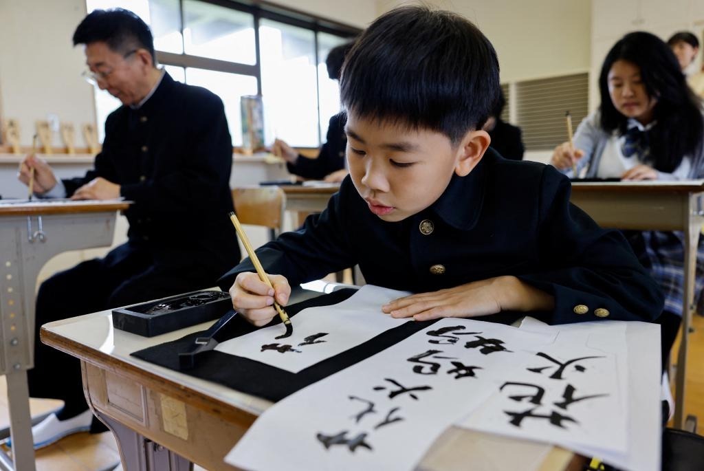 一名來自中國的遊客（中）穿上日本校服練習書法。