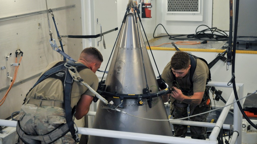 美军士兵在发射井工作，将钛护罩固定在「义勇兵3型」洲际弹道导弹顶部。 美联社）