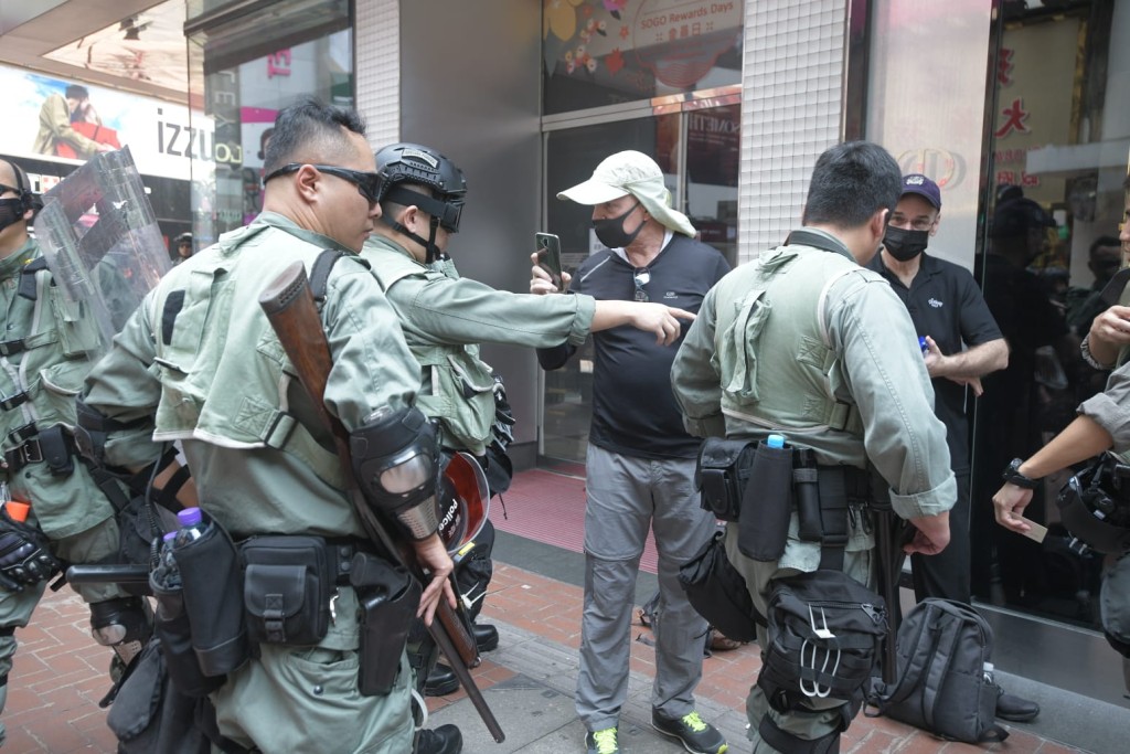 防暴警搜查在場的黑衣人士。