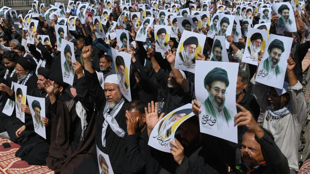 伊朗民眾手持肖像，宣誓效忠新領袖穆傑塔巴。 美聯社