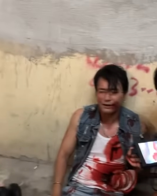 照片中可以看到林耀聲身穿一件牛仔外套及白色背心,他心口及腹部位置都有大片血跡,並且口吐鮮血,十分虛弱地坐在地上。 照片中可以看到林耀聲身穿一件牛仔外套及白色背心,他心口及腹部位置都有大片血跡,並且口吐鮮血,十分虛弱地坐在地上。