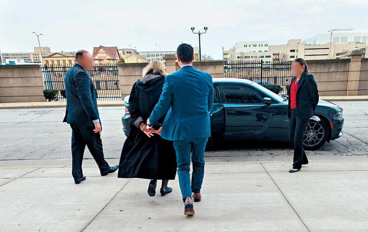 女法官杜根周五被捕後由執法人員押走。