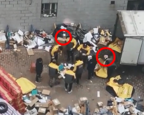 6名穿著制服的快递员及两名穿黑衣的工作人员站在原地不动「分拣」包裹。影片截图