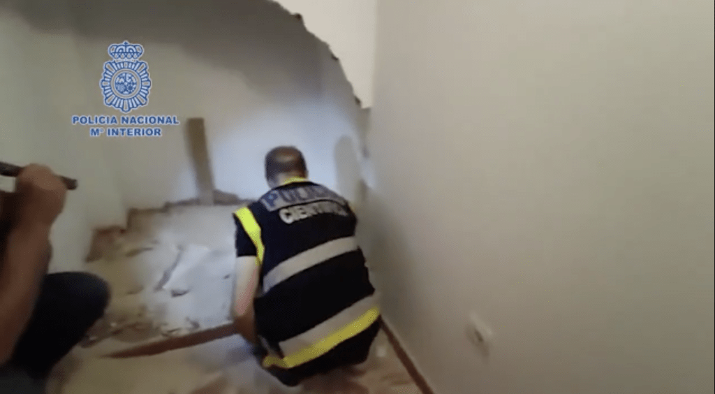警方在砸开的墙壁间搜索证据。