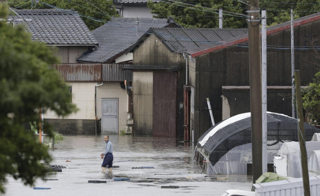 日本南部福岡縣久留米市，一名男子大雨中涉水穿過街道。AP